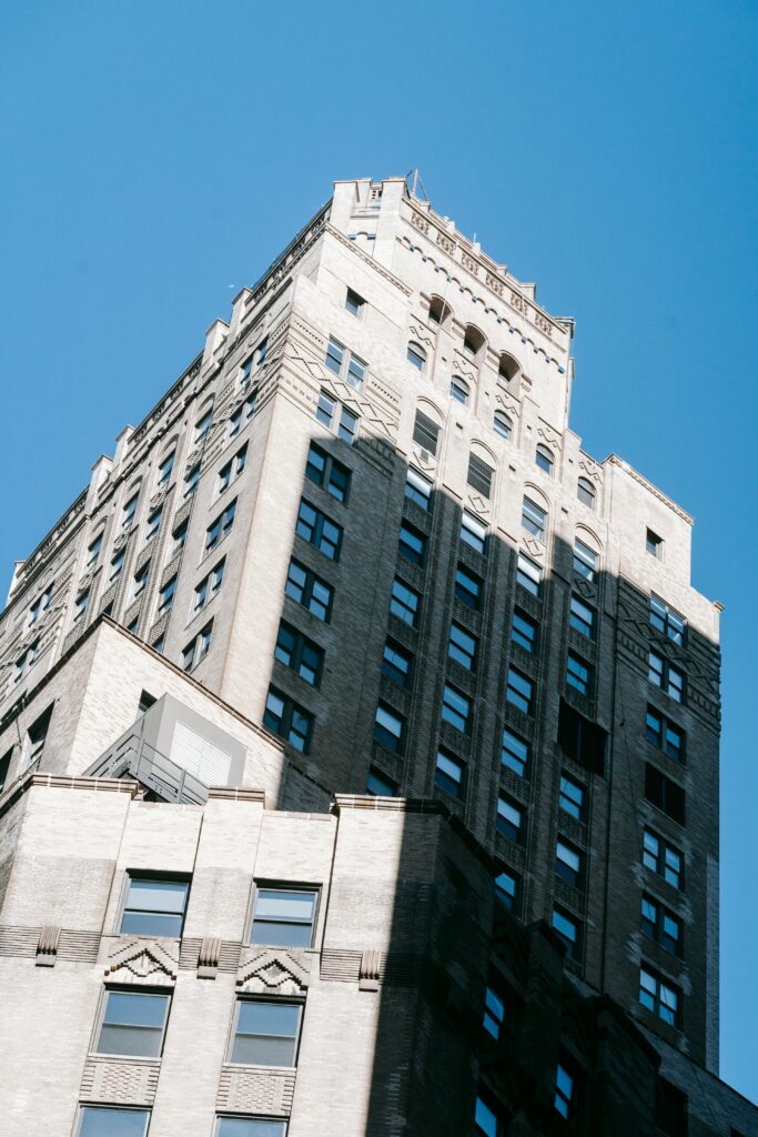 From below of old multistory building with stone decorative elements located against blue sky