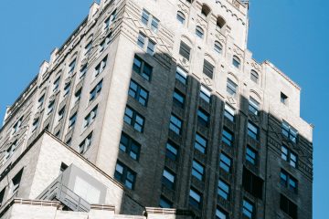 From below of old multistory building with stone decorative elements located against blue sky